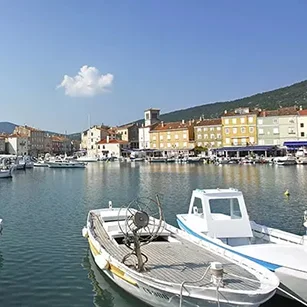 Luka u Cresu s brodicama i starogradskom rivom pod vedrim nebom