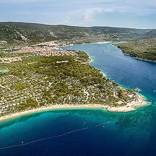 Panoramski pogled na Kamp Kovačine na Cresu s tirkiznim morem i zelenom obalom